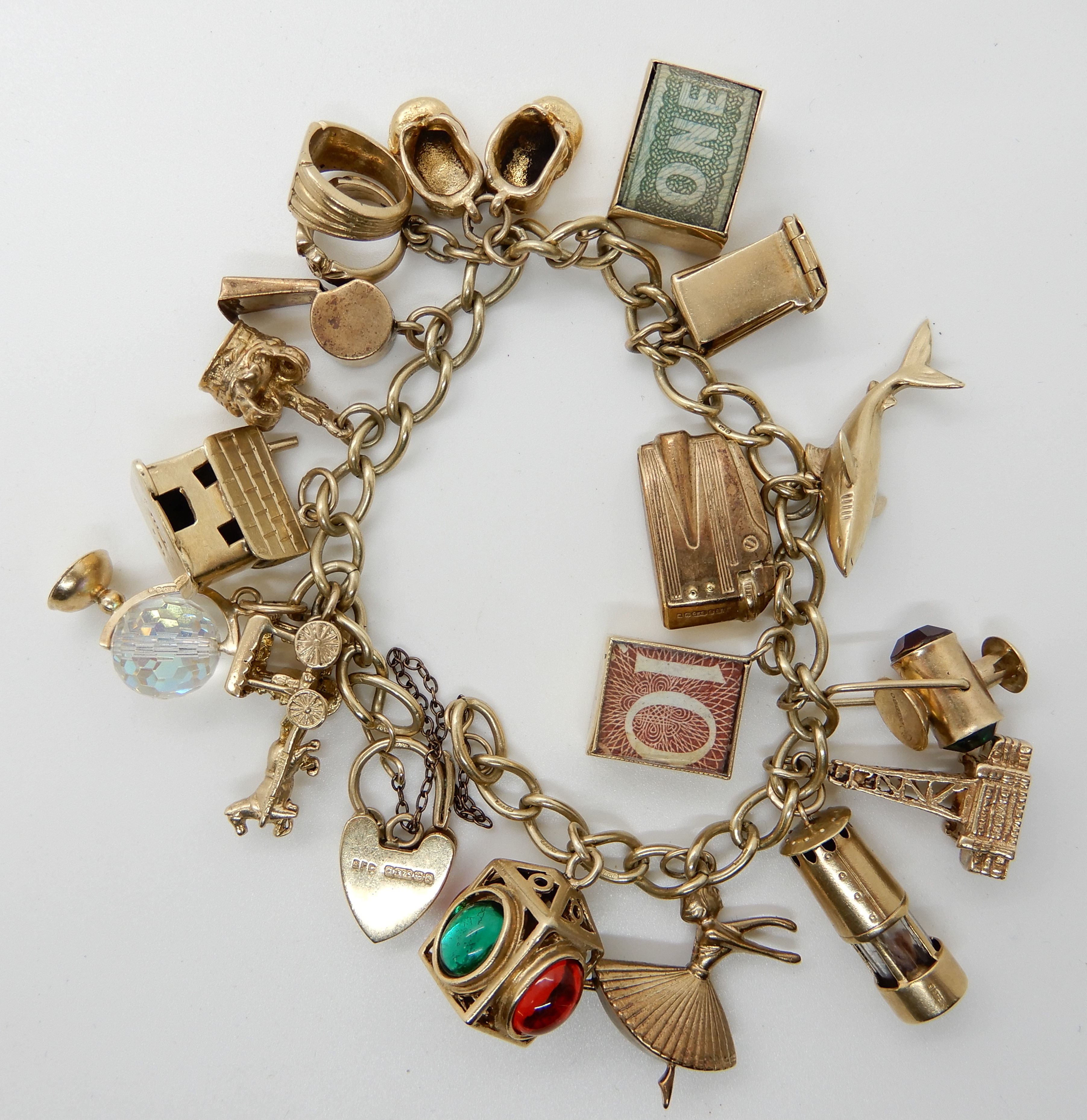 A 9ct gold charm bracelet with heart shaped clasp and seventeen 9ct gold and yellow metal charms