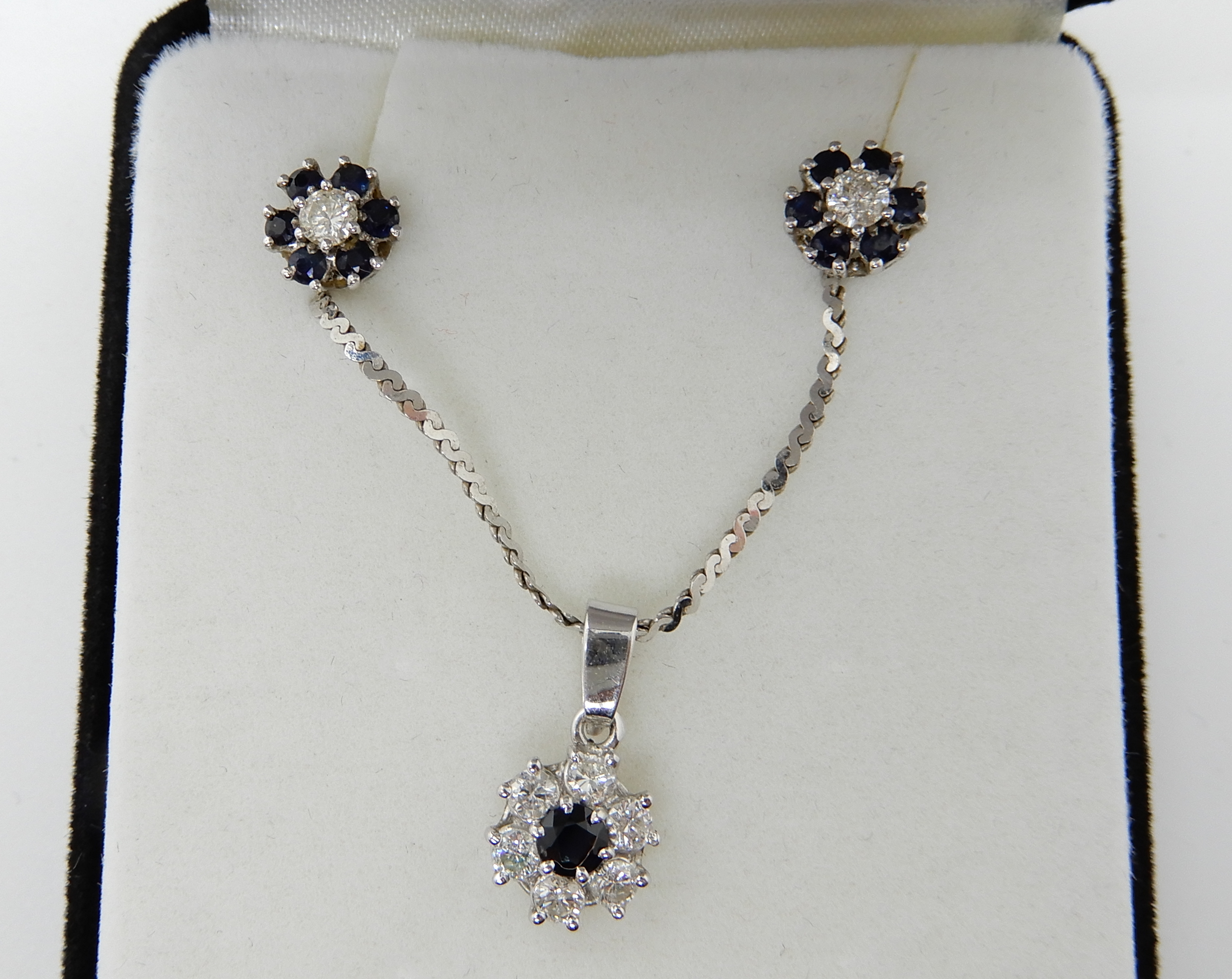 An 18ct white gold diamond and sapphire flower pendant with matching earrings, estimated approx