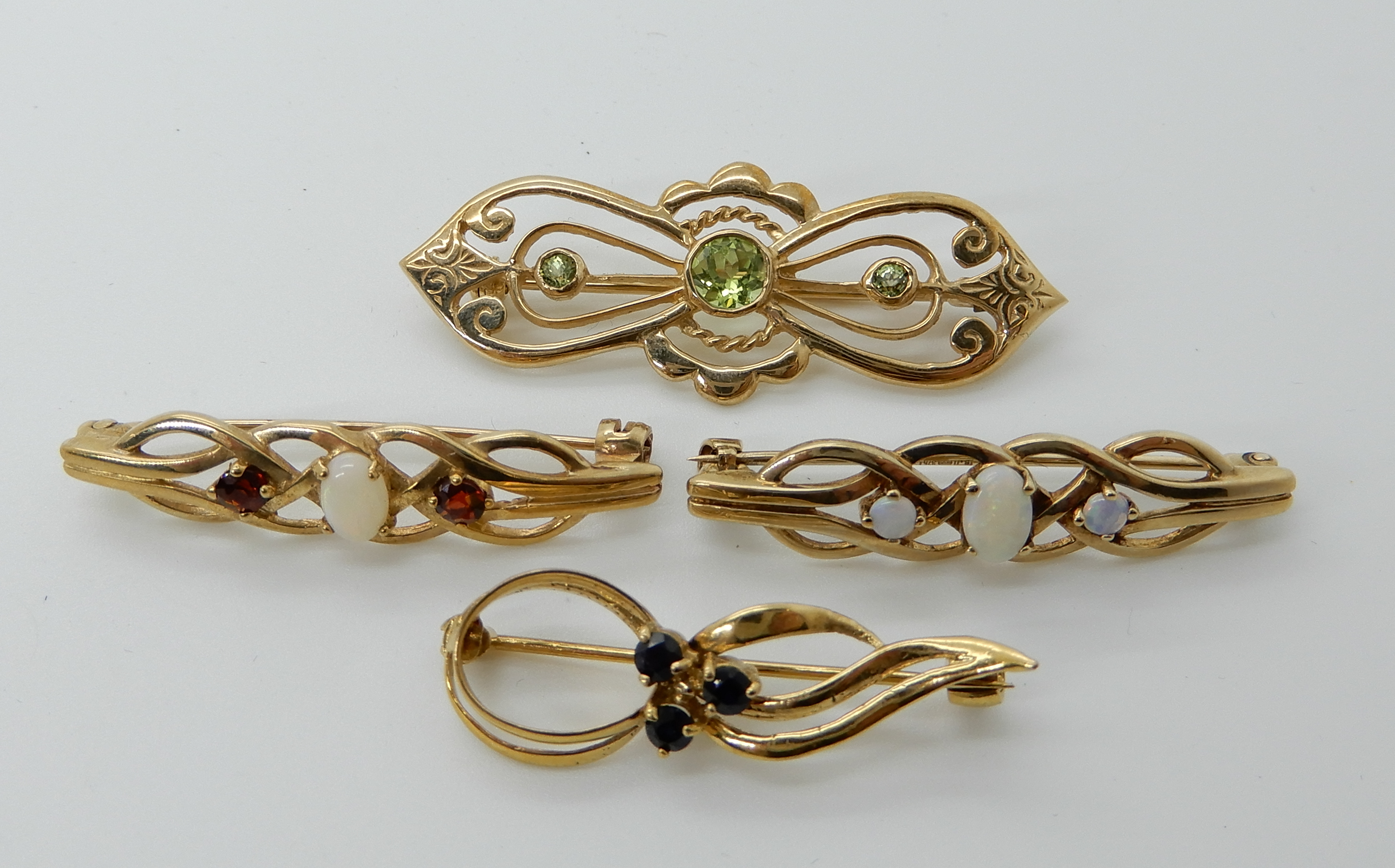 A 9ct gold peridot brooch, length 4.5cm, two 9ct opal set brooches and a 9ct sapphire example