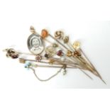 A collection of gold and yellow metal stick pins to include a 9ct locket example, others with