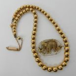 A 15ct gold bead necklace, length 36cm, weight 12.3gms and a bright yellow metal elephant brooch 2.