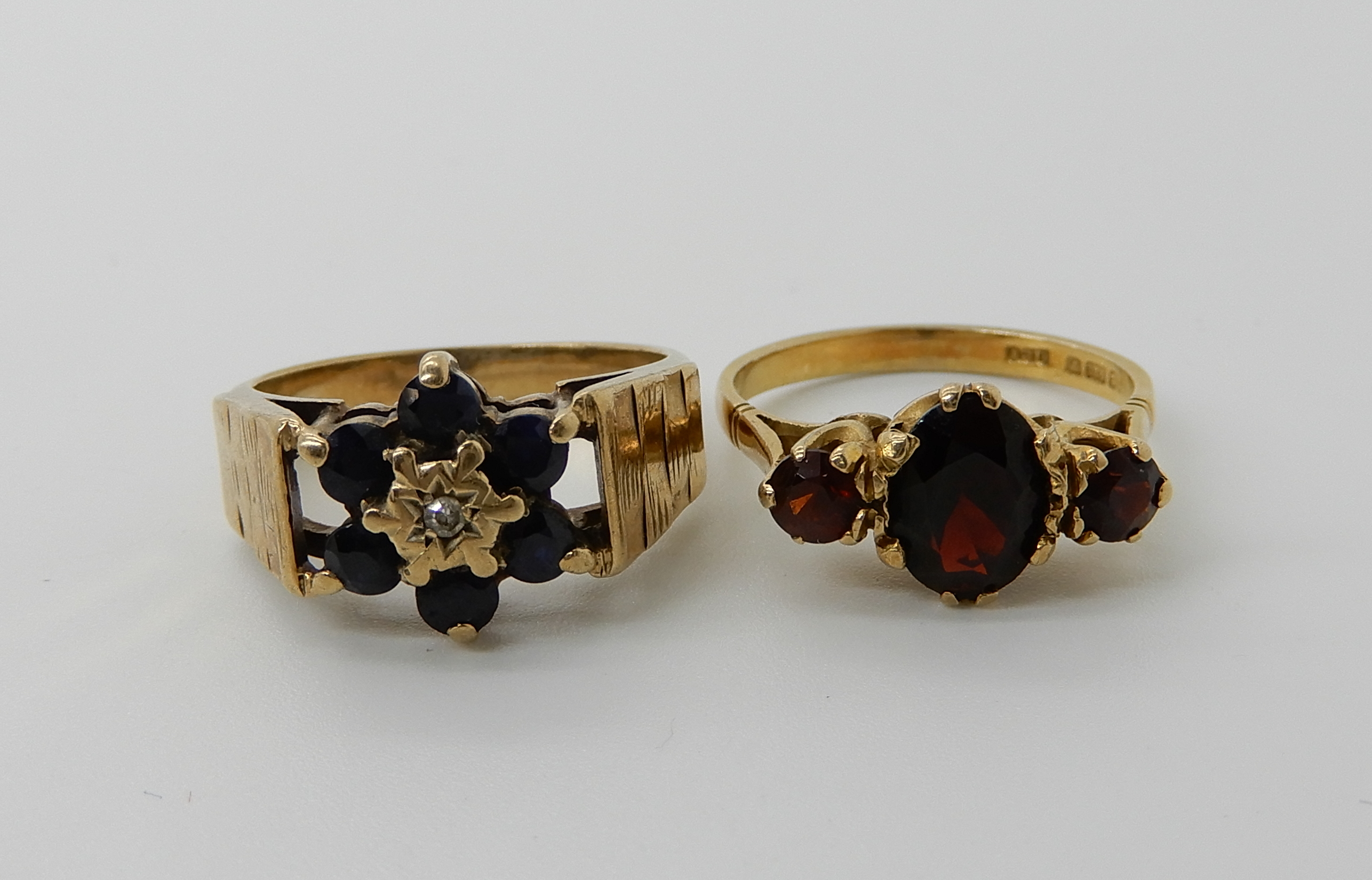 A 9ct gold retro sapphire and diamond flower cluster, size N1/2, a 9ct three garnet ring size N,