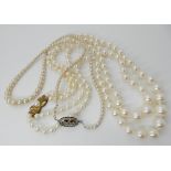 Two strings of faux pearls one with a vintage 18ct diamond set clasp set with approximately 0.