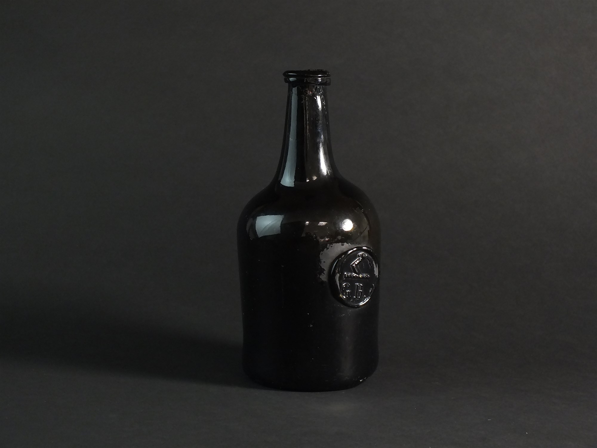 An 18th century green glass wine bottle with 'G.B' seal