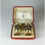 A cased pair of Adams style silver gilt pepper pots