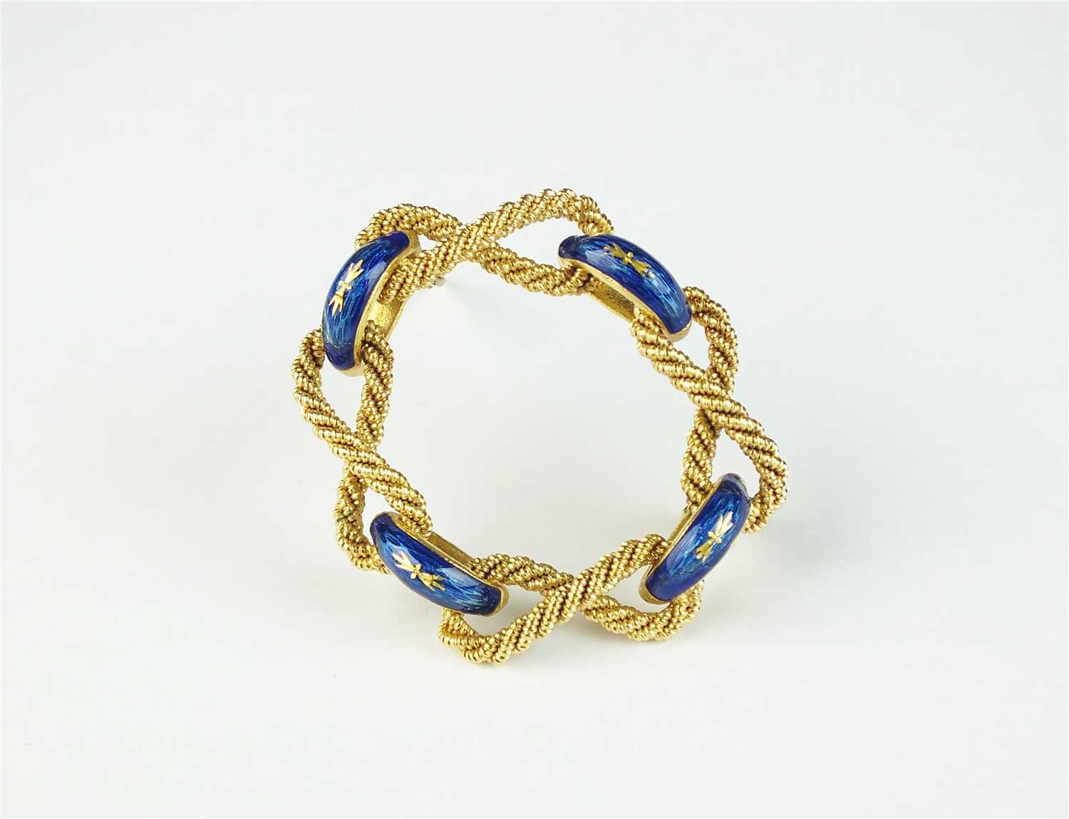 An yellow metal and blue enamel stylised rope brooch