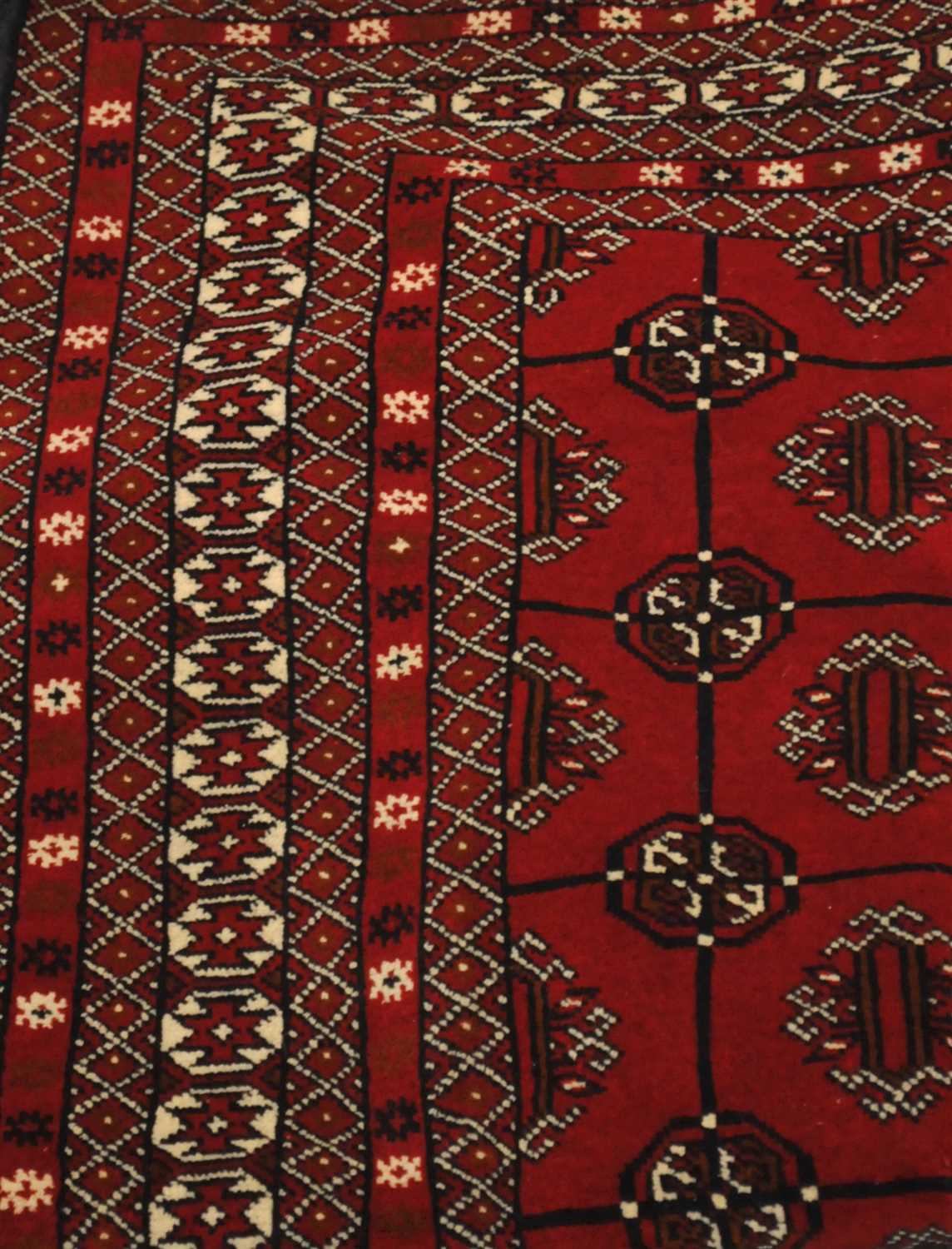 An Afghan Turkmen rug, the blood red field of guls enclosed by multiple narrow borders, 173cm x
