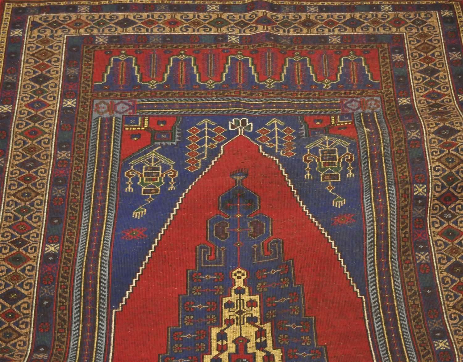 An Anatolian rug, the raspberry lozenge field centered by an indigo medallion, enclosed by