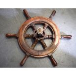 AN EARLY 20TH CENTURY CARVED WOODEN SHIPS WHEEL, with six turned spokes and brass hub. 63 cm wide.