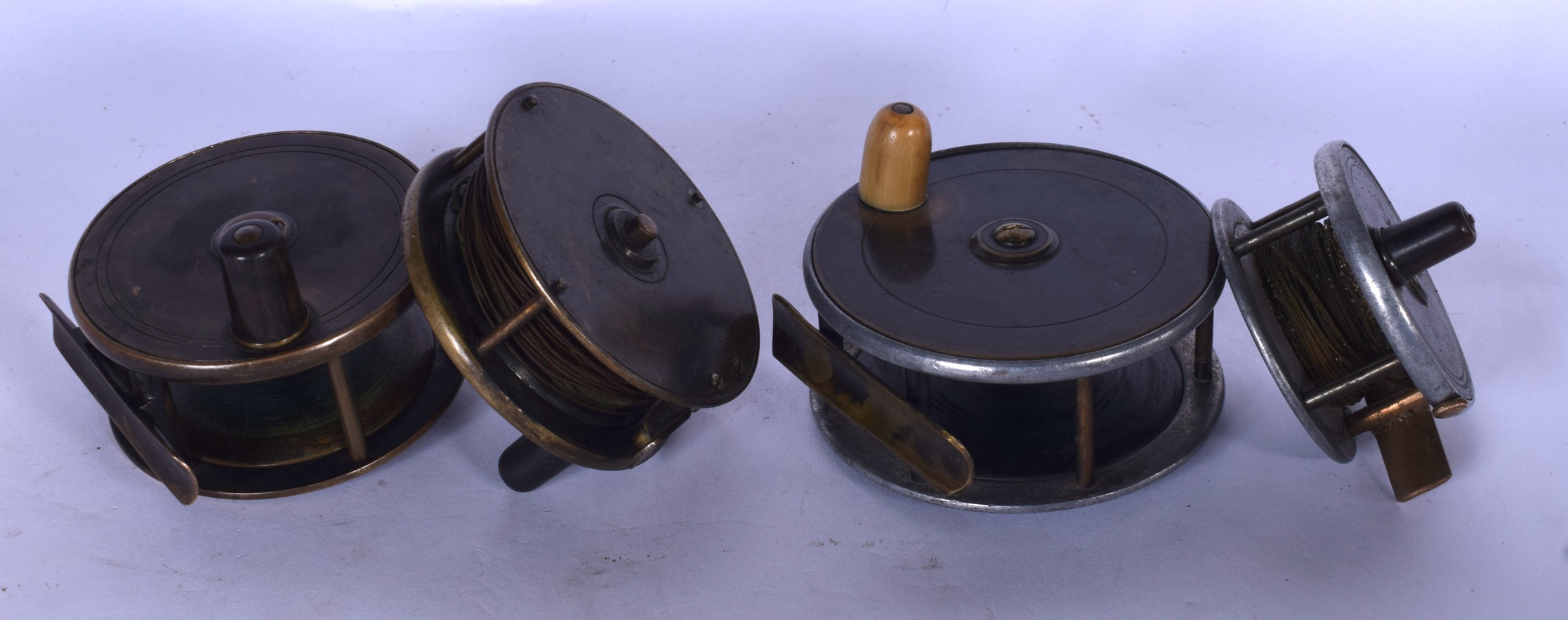 A GROUP OF FOUR ANTIQUE FISHING REELS, of varying size. Largest 10 cm.