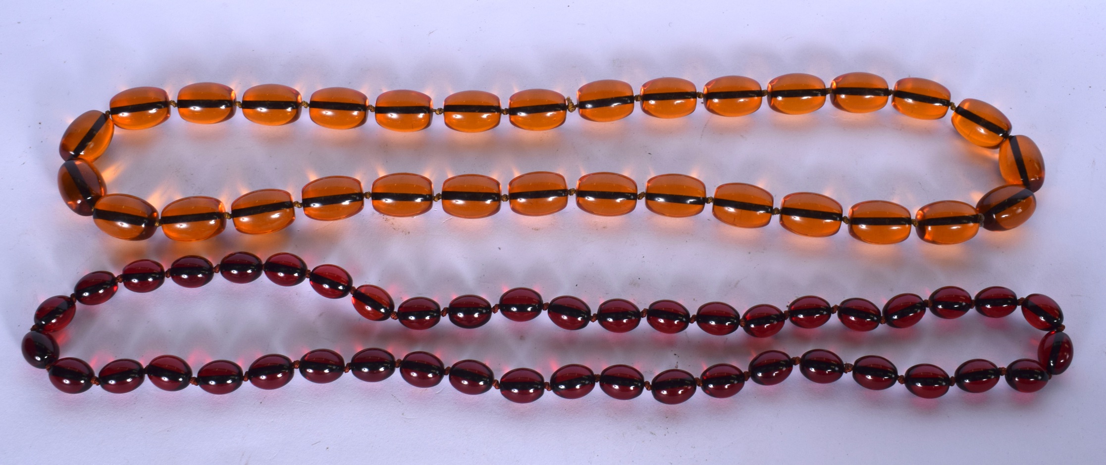 A LARGE AMBER TYPE NECKLACE, together with a similar. Largest bead 2.1 cm and total length 86 cm