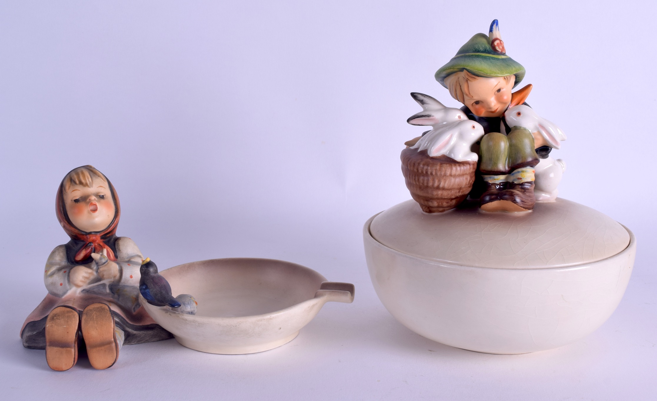 A GERMAN GOEBEL HUMMEL BOWL AND COVER formed with a boy holding rabbits, together with a figural