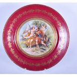 A RED GROUND EUROPEAN PORCELAIN DISH, decorated a male wearing armour with an angel and cherub