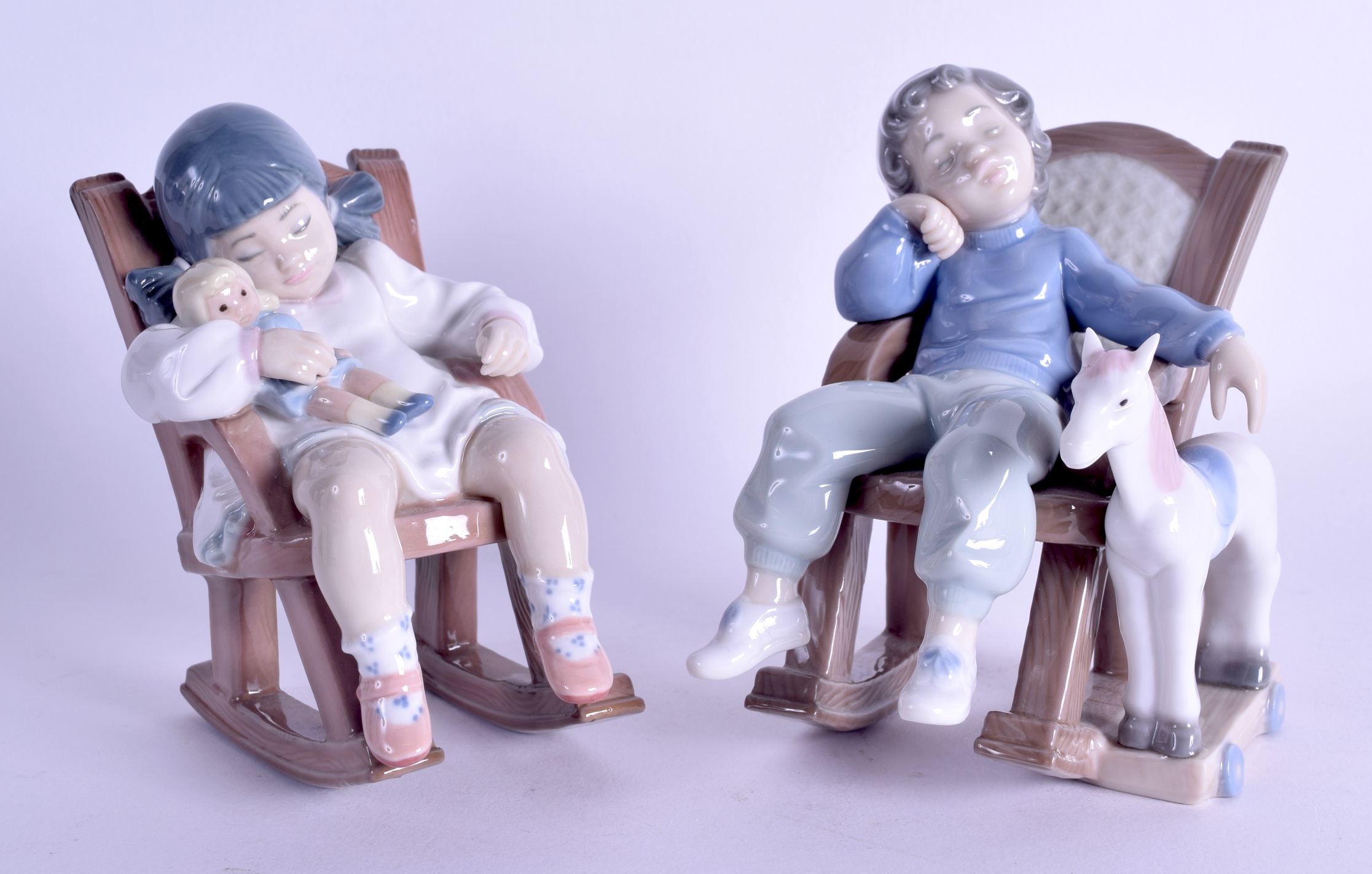 A PAIR OF LLADRO PORCELAIN FIGURES OF SLEEPING CHILDREN modelled upon chairs. 14 cm high.