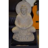 A LARGE MIDDLE EASTERN CARVED STONE FIGURE OF GANDHARA, modelled sat upon a lotus. 68 cm x 37 cm.