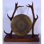 A LARGE BRASS TABLE GONG, with hammered decoration, supported by a pair of antlers. 46 cm high.