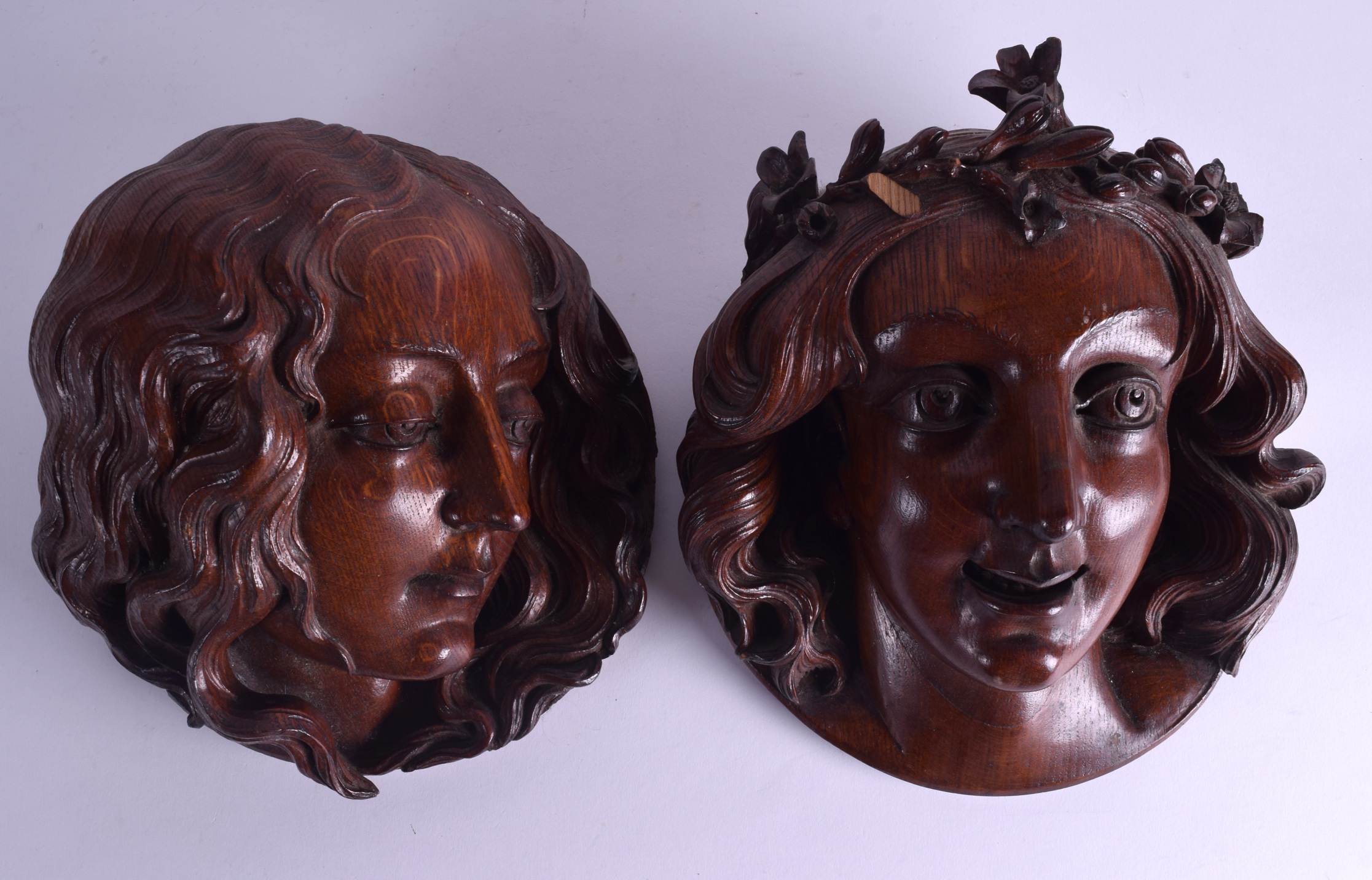 A LOVELY PAIR OF ENGLISH ARTS AND CRAFTS CARVED OAK WALL PLAQUES in the form of female mask heads.