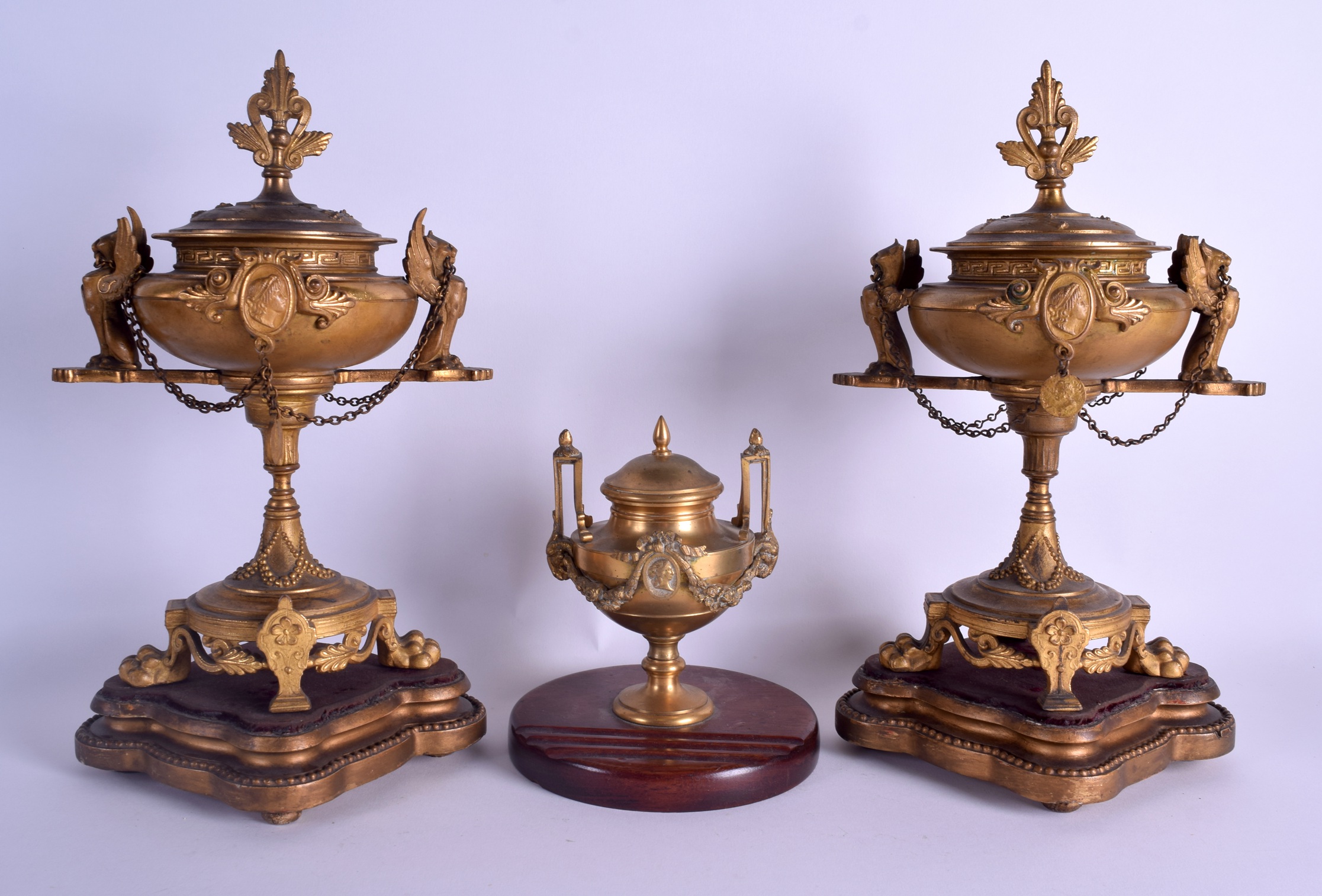 A 19TH CENTURY FRENCH GILT METAL MANTEL GARNITURE formed with two griffin mounts urns & a smaller