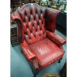 A LARGE EARLY 20TH CENTURY WINGBACK ARMCHAIR, with button back red leather upholstery on square