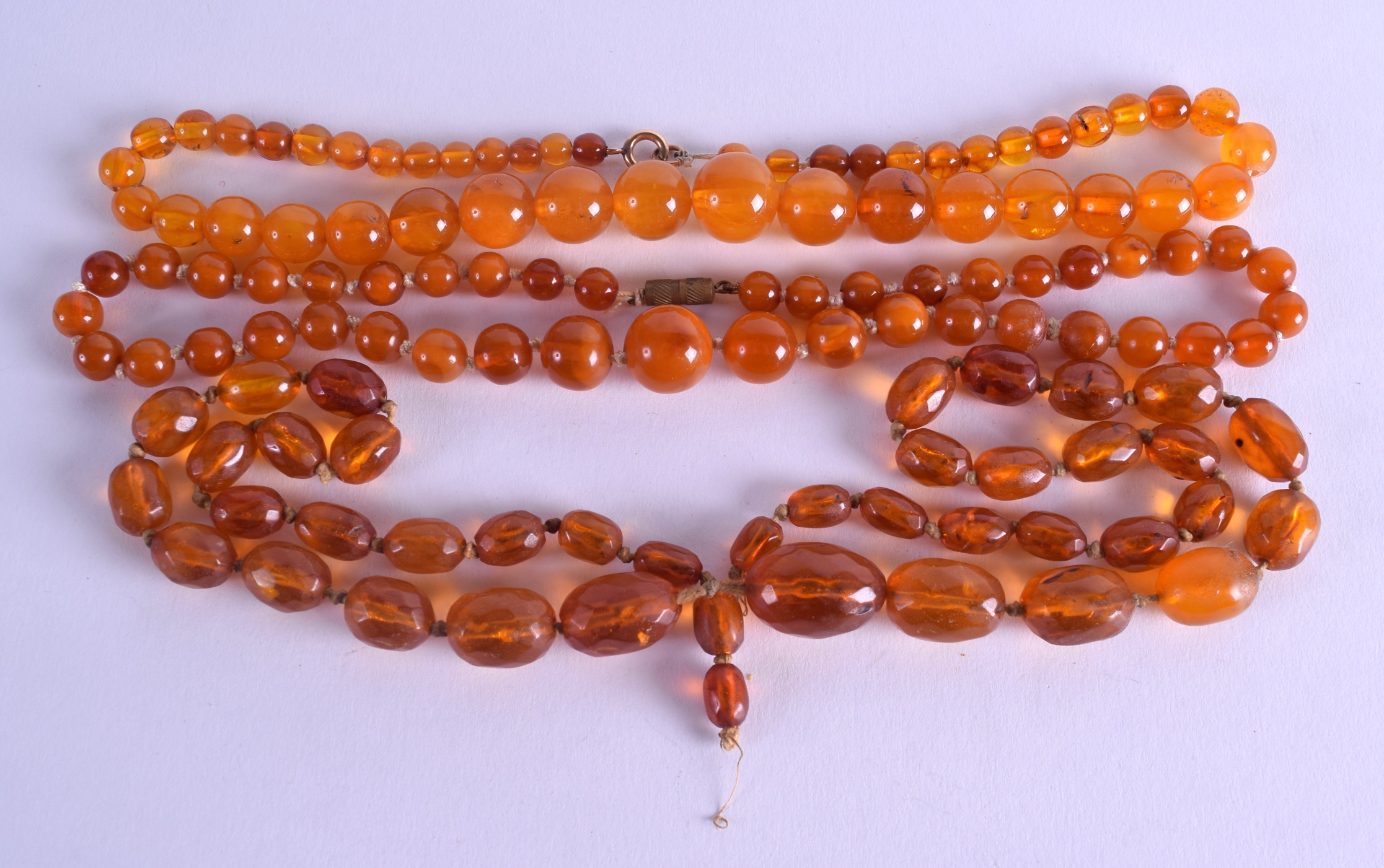 THREE AMBER TYPE NECKLACES. 90 grams. (3)