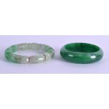 TWO CHINESE CARVED HARDSTONE BANGLES possibly jadeite. 7.5 cm & 7 cm diameter. (2)