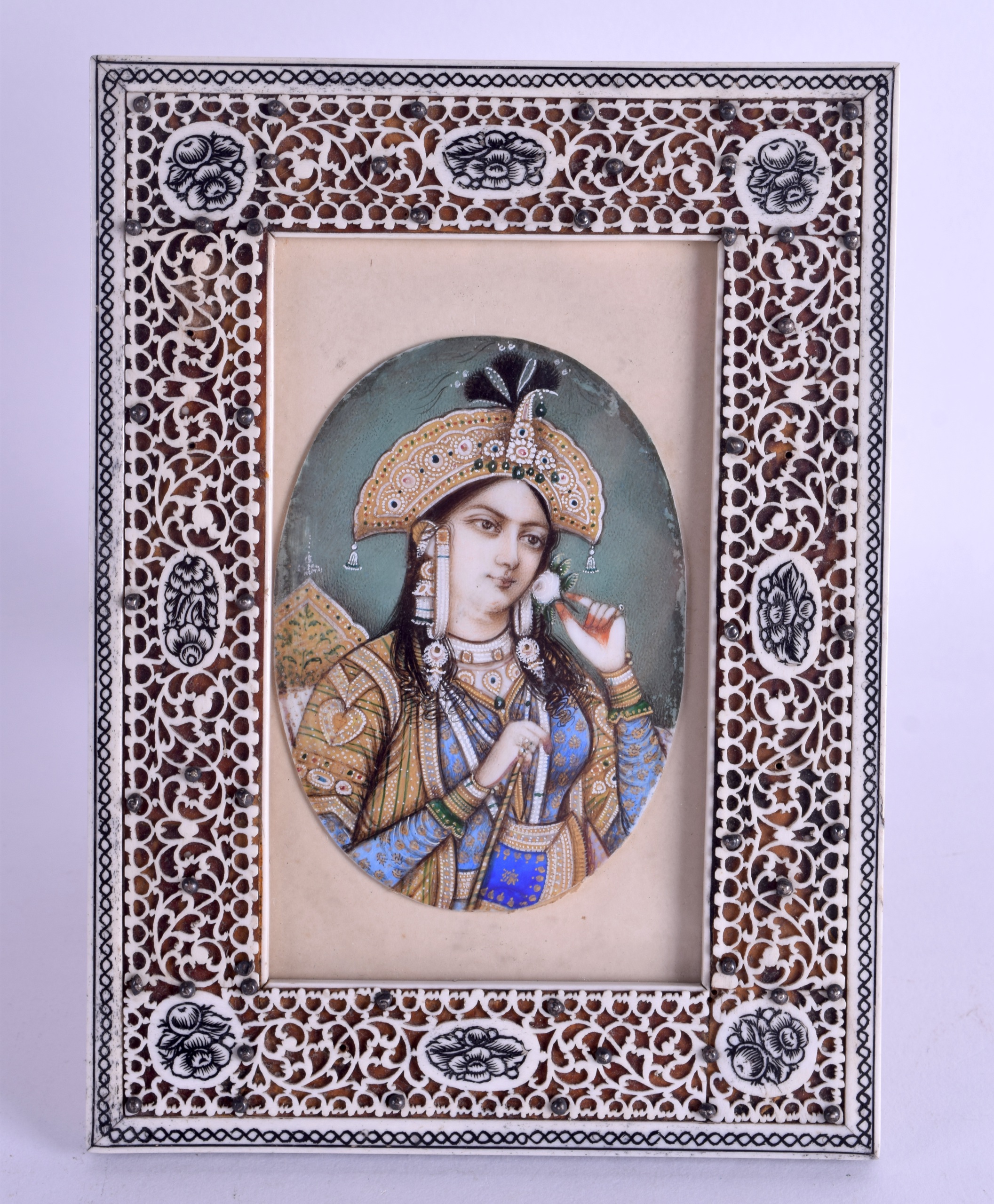 A 19TH CENTURY INDIAN PAINTED IVORY PORTRAIT MINIATURE depicting a female within a green interior.