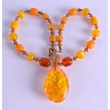 A CHINESE TIBETAN CARVED AMBER NECKLACE. 40 cm long, pendant 8 cm x 3 cm.