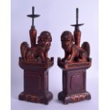 A PAIR OF 19TH CENTURY CHINESE LACQUERED WOOD PRICKET STICKS modelled as buddhistic dogs of foe upon