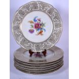 A SET OF SEVEN GERMAN PORCELAIN PLATES, decorated with precious objects and bold central floral spra