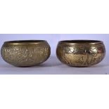 A MATCHED PAIR OF EARLY 20TH CENTURY INDIAN BRASS BOWLS, one decorated in relief with figures, the o