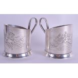 A PAIR OF EARLY 20TH CENTURY RUSSIAN WHITE METAL GLASS HOLDERS decorated with troika. 9.4 oz. 9 cm w