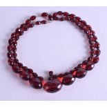 AN EARLY 20TH CENTURY RED AMBER NECKLACE of facetted form. 48 grams. 84 cm long, largest bead 2.75 c