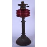 A VICTORIAN OIL LAMP, formed with a ruby glass shape on column supports. 51 cm high.