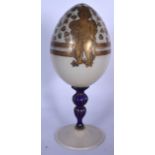 A RARE EARLY 20TH CENTURY RUSSIAN GLASS EASTER EGG, supported on a deep blue twist stem and painted