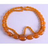 AN EARLY 20TH CENTURY AMBER TYPE NECKLACE of graduated form. 66 grams. 86 cm long, largest bead 2.75