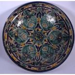 A LARGE ISLAMIC POTTERY BOWL OR DISH, decorated with stylised foliage and a raised foot. 37.5 cm wid