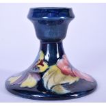 A MOORCROFT POTTERY CANDLESTICK HOLDER, blue ground and decorated with foliage. 8.5 cm x 10 cm.