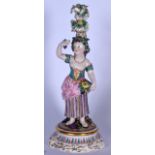 AN EARLY 20TH EUROPEAN PORCELAIN CANDLESTICK FIGURE OF A FEMALE, modelled standing holding a bunch o