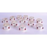 A SET OF TWELVE SILVER PLATED NAPKIN RINGS set with red stones. (12)