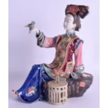 A 1950S CHINESE BISQUE GLAZED POTTERY FIGURE OF A FEMALE modelled holding a parrot. 25 cm x 18 cm.