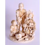 A FINE 19TH CENTURY JAPANESE MEIJI PERIOD CARVED IVORY OKIMONO modelled as a father and son beside m