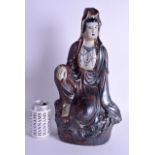 A LARGE 19TH CENTURY CHINESE STONEWARE FIGURE OF GUANYIN modelled upon a naturalistic outcrop. 43 cm