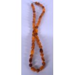 A LONG AMBER TYPE NECKLACE, the beads naturalistic in shape. 74 cm long (largest bead 1.8 cm)