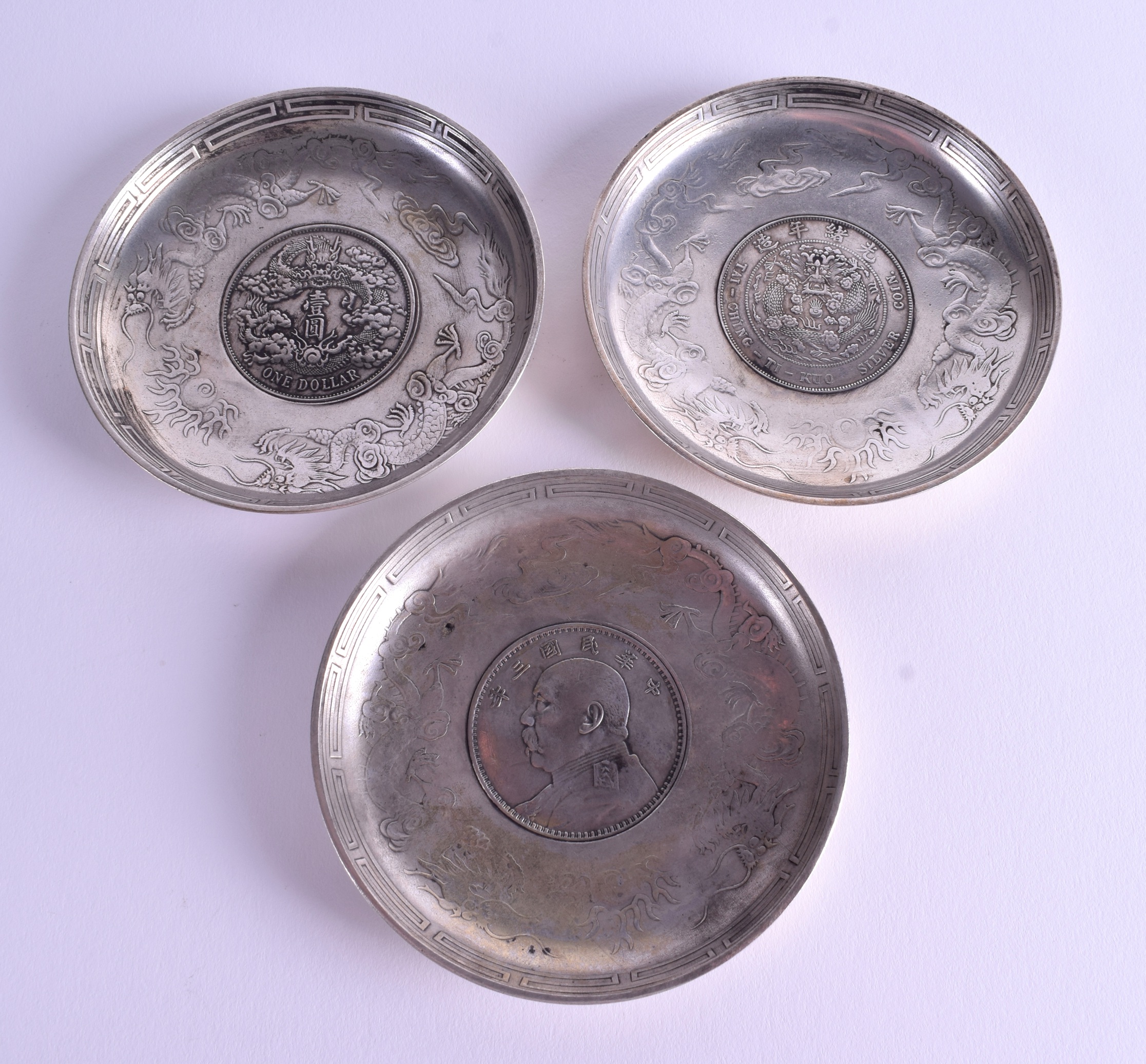 THREE CHINESE WHITE METAL COIN DISHES. 9 cm wide. (3)