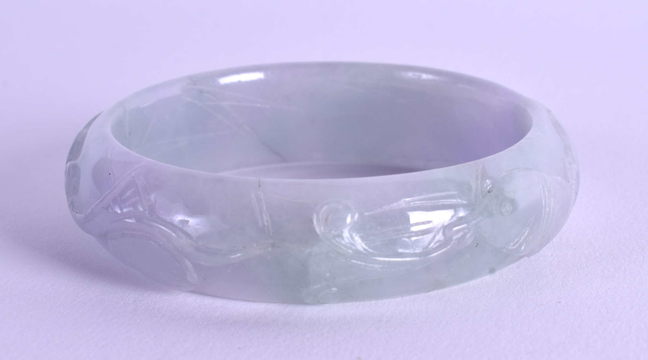 A CHINESE CARVED JADEITE BANGLE. 7 cm wide.