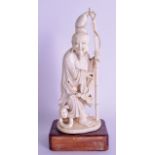 A 19TH CENTURY CHINESE CARVED IVORY FIGURE OF A FISHERMAN modelled holding a fish upon a circular ba