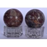 A PAIR OF EARLY 20TH CENTURY RED MARBLE SPHERE SHAPED SCULPTURE, formed upon shaped glass bases. 13.