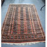 AN ORANGE GROUND PERSIAN TEKKE TURKMEN RUG, decorated with motifs and symbols, encased within a geom