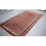 AN EARLY 20TH CENTURY BROWN GROUND BALUCH RUG, decorated with Geometric symbols. 236 cm x 136 cm.