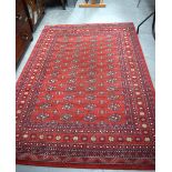 A RED GROUND PERSIAN TEKKE TURKMEN RUG, decorated with geometric symbols and motifs, within a floral